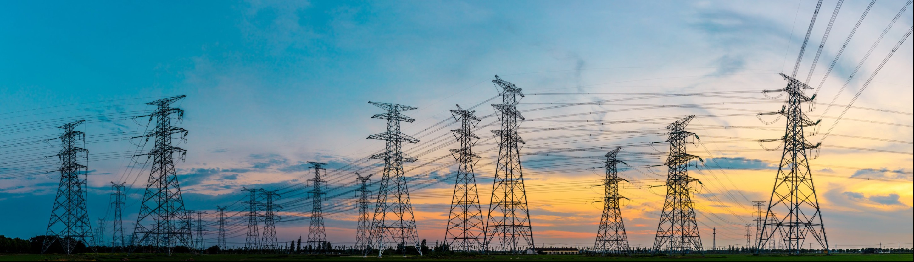 Power lines and towers against sky and sunset background